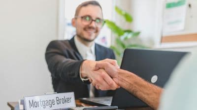 Mortgage broker shaking hands with client in office